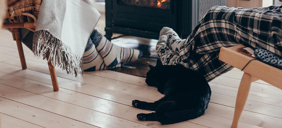 Black cat lay on floor next to fire