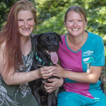 Mutley's owner and a PDSA vet give him a hug and show the kebab skewer he swallowed
